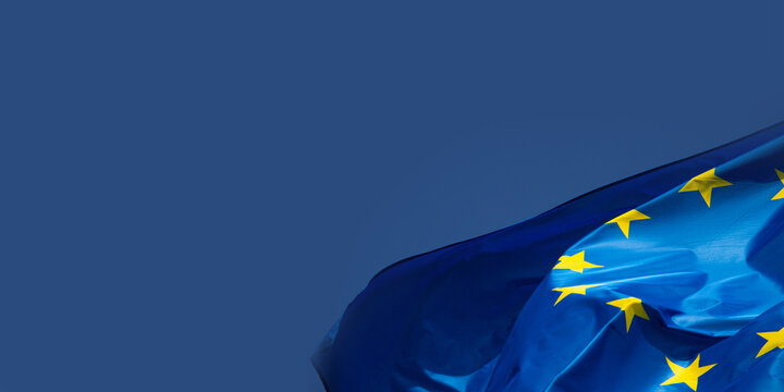 Drapeau de l&rsquo;Union europ&eacute;enne flottant sur fond bleu, symbolisant l&rsquo;unit&eacute;, la coop&eacute;ration et les valeurs communes du continent europ&eacute;en, pouvant servir d'arri&egrave;re-plan. Emplacement pour le texte.