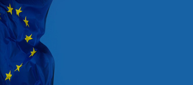Drapeau de l&rsquo;Union europ&eacute;enne flottant sur fond bleu, symbolisant l&rsquo;unit&eacute;, la coop&eacute;ration et les valeurs communes du continent europ&eacute;en, pouvant servir d'arri&egrave;re-plan. Emplacement pour le texte.