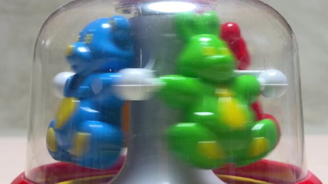 Plastic animal figures spin rapidly inside a clear dome. This kinetic action produces a light, rhythmic rattling and a continuous plastic whirring sound as the mechanism rotates.