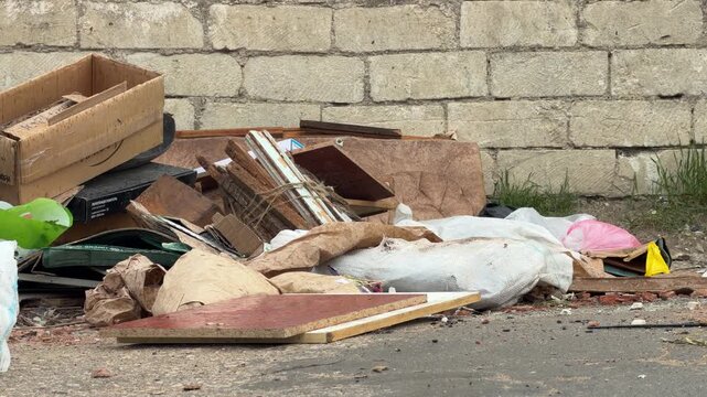 Discarded boxes and white sacks clutter the worn pavement. This messy scene creates a feeling of sadness and neglect in the urban alley. It looks lonely and forgotten.