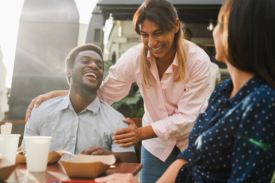 Multiracial people eating at food truck restaurant outdoor - Summer lifestyle and food concept - Main focus on african man face