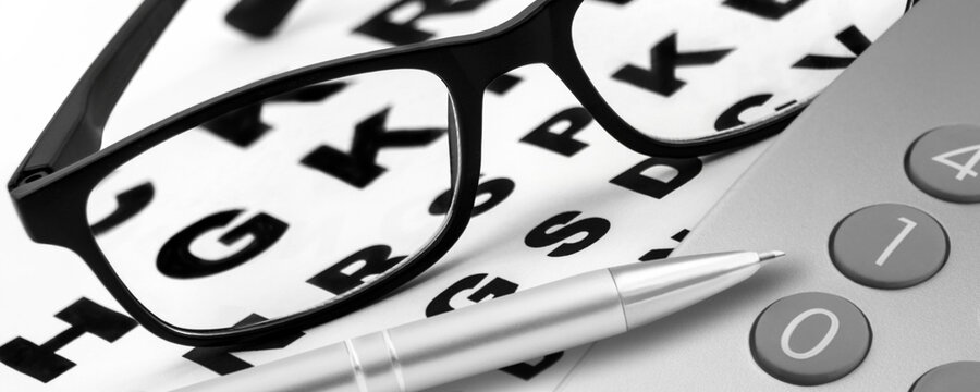 Pair of glasses and calculator with eye chart eyesight test