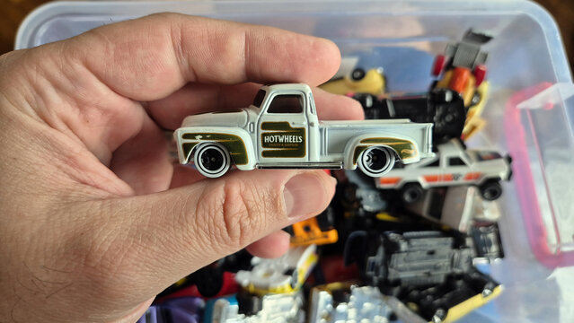 Hand holding a white Hot Wheels 1956 Ford F-100 toy truck with gold "Parts & Repair" decals. Picture taken on April 21, 2026 in Bucharest, Romania.