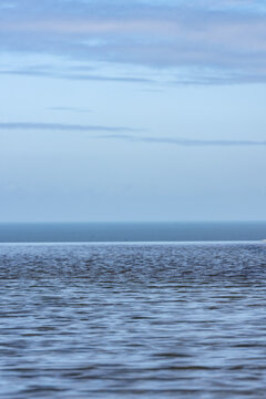 Vue paisible de l'horizon marin sous un ciel nuageux avec une surface de l'eau scintillante et l&eacute;g&egrave;rement ondul&eacute;e.