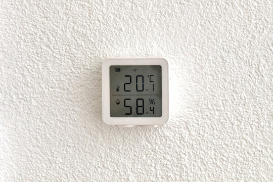 Digital Thermometer Hygrometer on White Wall Showing Room Temperature and Humidity Indoor Climate Control Device