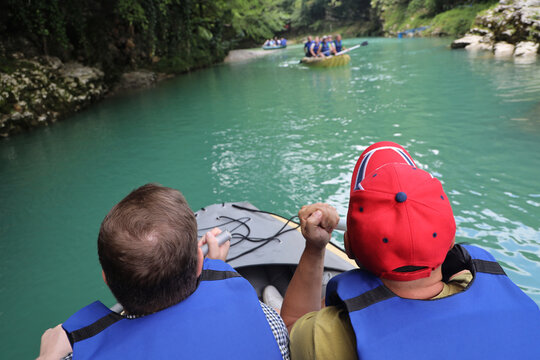 back rear view of Tourists in rubber boats enjoying views of Abasha river erosion canyon in Samegrelo region of Georgia. Martvili Canyon. male with paddles wear saving vest group op people floating