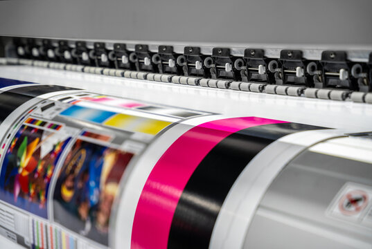 Large offset printing press or magazine running a long roll off paper in production line of industrial printer machine.