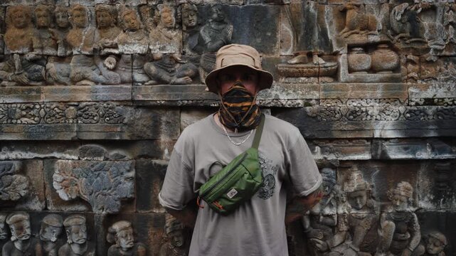 Cinematic footage of a man walking through the ancient Borobudur Temple in Indonesia. Stone stupas, intricate carvings, and spiritual atmosphere create a peaceful and reflective scene.