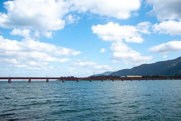 Obraz premium 京都府 宮津市の絶景 海のような由良川橋梁を走るローカル線の風景(Spectacular view of Yuragawa Bridge and local train in Miyazu, Kyoto)