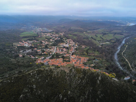 Aerial view of the historic village and castle ruins surrounded by green hills and the Tet river in Rodes, Occitanie, France.