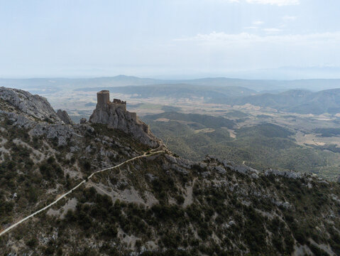 Aerial view of Chateau de Queribus perched on a rugged limestone ridge overlooking the vast valley and rolling hills Cucugnan, Occitanie, France.