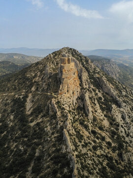 Aerial view of the historic Chateau de Queribus ruins perched on a steep rocky ridge surrounded by the rugged landscape of Cucugnan, Occitanie, France.