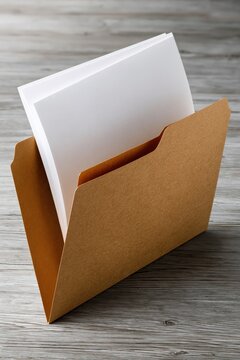Open kraft folder holding white papers on wooden table