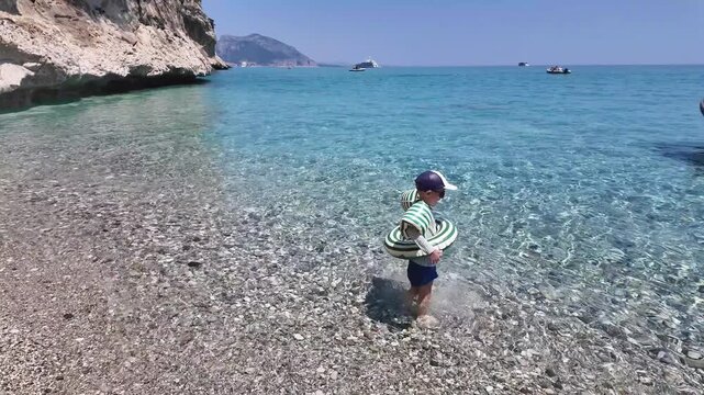 Child practicing safe behavior in the sea with flotation device.