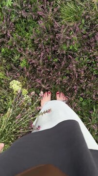 An overhead view of barefoot women standing among wildflowers, holding a bouquet of wildflowers, their clothes fluttering in the wind. Oneness with nature, rest, relaxation, a natural and summery scen