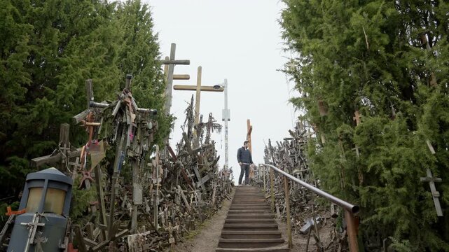 Tourist Visiting UNESCO Hill of Crosses in Lithuania, Cinematic Exploration of Kryžių kalnas Pilgrimage Site