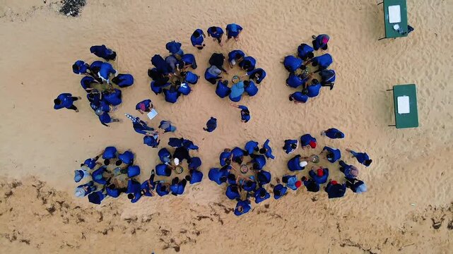 Top View Beach Crowd Forming Patterns with Blue Umbrellas Drone 4KClip