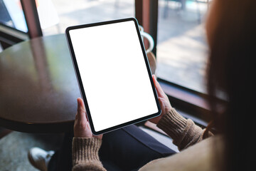 Mockup image of a woman holding digital tablet with blank white desktop screen in cafe © Farknot Architect