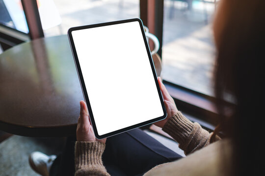 Mockup image of a woman holding digital tablet with blank white desktop screen in cafe