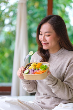 Vertical portrait image of a woman eating vegetables salad at home, Vegan, Clean food, dieting concept