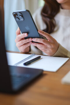 Apr 14th 2026 : Vertical image of a woman using Iphone 15 Pro max smartphone and laptop computer at home, Chiang mai Thailand