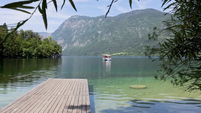 Crystal Clear Water of Lake Bohinj with Wooden Pier and Boat, Slovenia