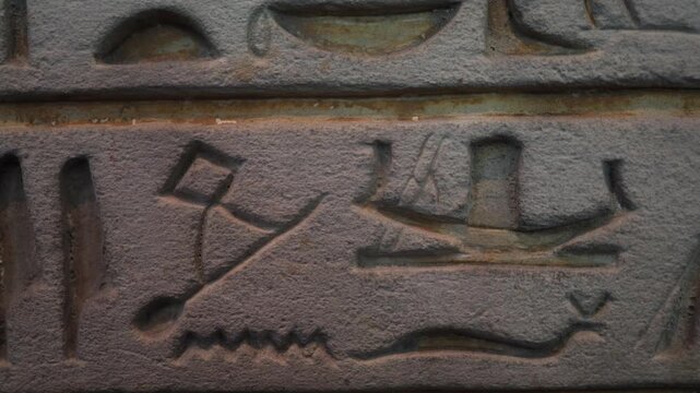 Ancient egyptian hieroglyphs carved on a stone wall, symbolizing the history, culture, and language of pharaonic civilization, moving with a subtle light effect
