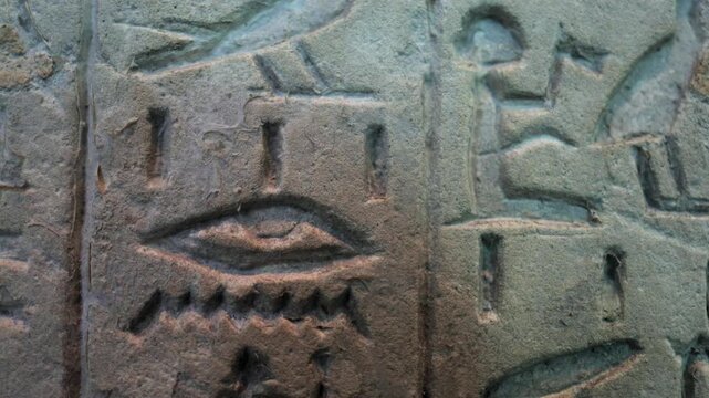 Ancient egyptian hieroglyphs, including the eye of ra and other sacred symbols, carved on a weathered stone wall, representing the culture and history of ancient egypt