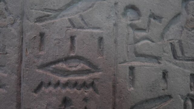 Ancient egyptian hieroglyphs carved on a temple stone wall featuring the eye of horus symbol while exploring historical ruins and discovering archaeological treasures