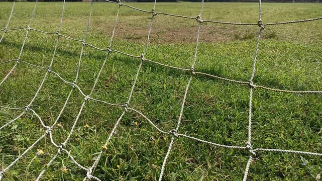 Close up of a soccer goal net with green grass background.