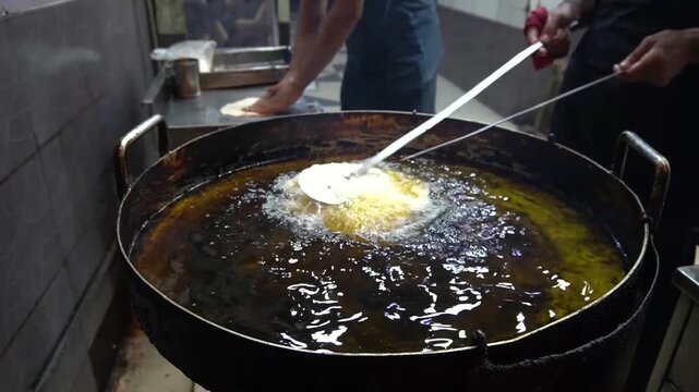 Paratha frying in bubbling oil with spatulas and street kitchen vibe, cooking action concept