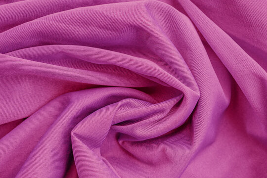 A vibrant macro shot of fuchsia synthetic fabric arranged in a tight, hypnotic spiral. The smooth, glossy material creates a deep gradient of electric pink and crimson