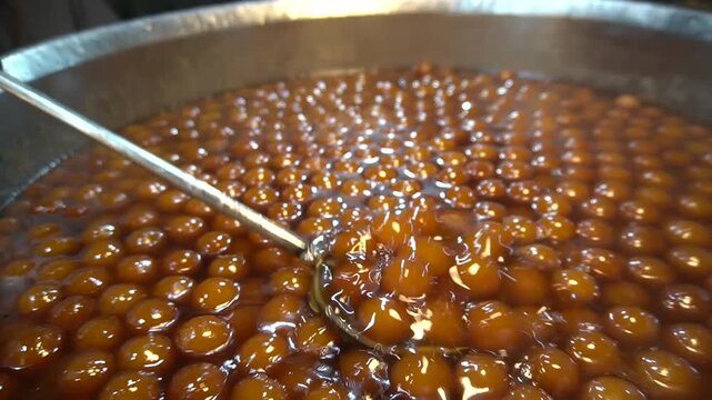Gulab jamun in syrup with ladle dripping sweet glaze, sweet syrup concept