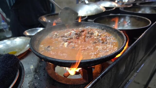 Karahi cooking on flame, rich curry bubbling in rustic pan, traditional curry concept