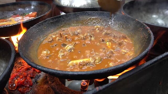 Karahi Stew cooking over fire in wok, rustic street kitchen scene, outdoor cooking concept