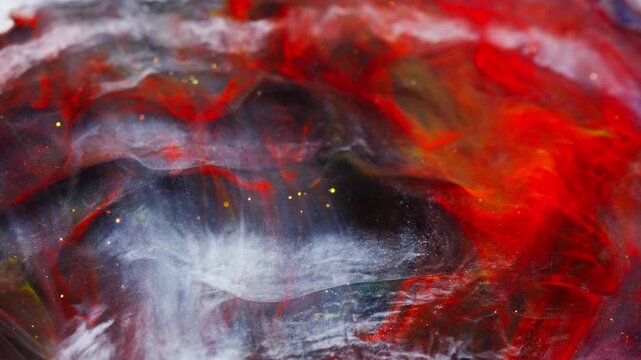 Abstract organic forms made with colorful red inks and golden glitters