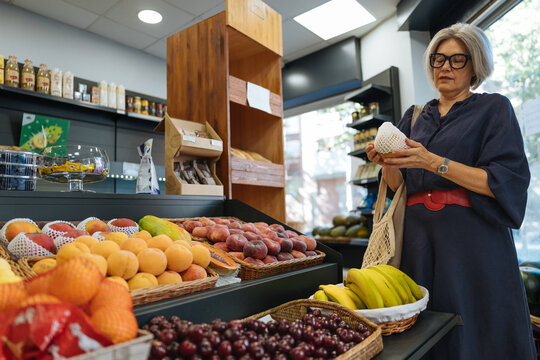 Senior woman choosing fresh fruit in grocery store