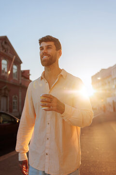 Happy man walking street enjoying morning coffee
