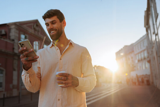 Man using smartphone and coffee on city street