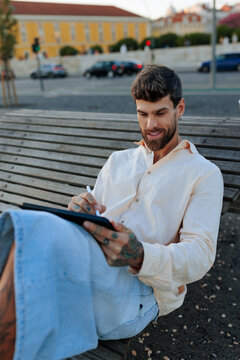 Man sketching on a digital tablet at urban park bench