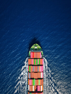 High aerial overhead view of a cargo container ship traveling over the ocean with copy space