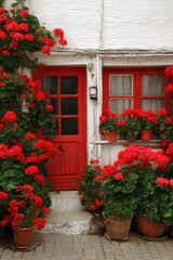 Fototapeta premium In a charming small town on a sunny day, a vibrant bright red door stands out, framed beautifully by a burst of blooming red flowers
