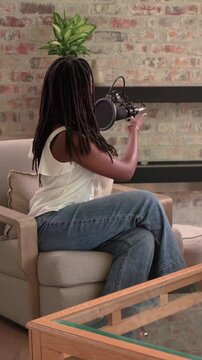 Vertical video: Entering woman holding phone, sitting in studio, speaking into mic for interview