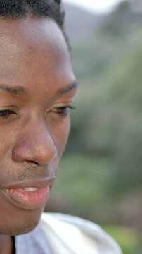 Vertical video: Camera filming man looking up and smiling to camera at hills in jacket, gray shirt