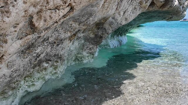 Transparent water washing under cliff edge. Ideal for travel and relaxation visuals.