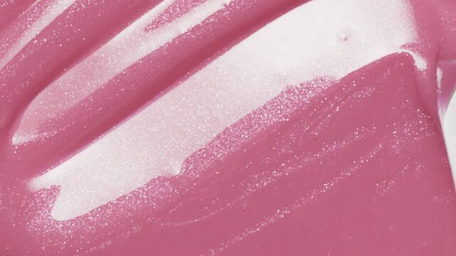 Close up of metal spatula smear pink lip gloss texture, satisfying texture stroke. Cosmetic product swatch background	
