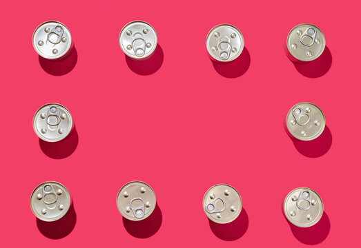 Frame of metal tin cans on pink background