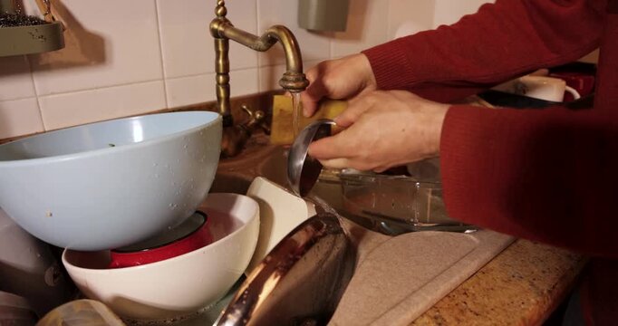 Man washing dirty dishes in a kitchen sink
