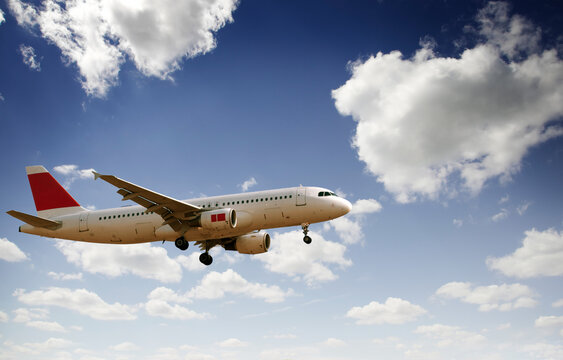 Commercial airplane flying in blue sky with clouds passenger jet landing travel aviation concept	