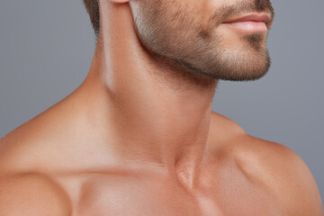 Naklejka premium Handsome male jawline and smooth neck skin with short beard and bare shoulders, warm lighting conveys healthy grooming and subtle confidence